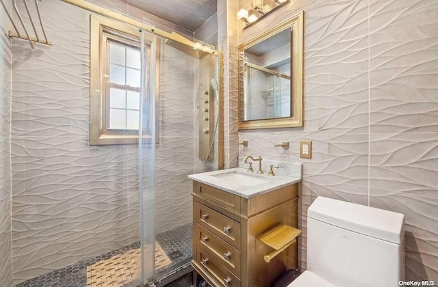 bathroom with walk in shower, vanity, tile walls, and toilet