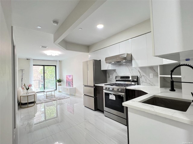 kitchen featuring white cabinetry, sink, tasteful backsplash, light stone counters, and appliances with stainless steel finishes