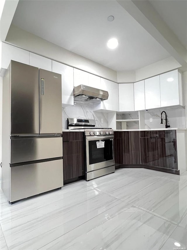 kitchen with decorative backsplash, appliances with stainless steel finishes, dark brown cabinets, ventilation hood, and white cabinetry