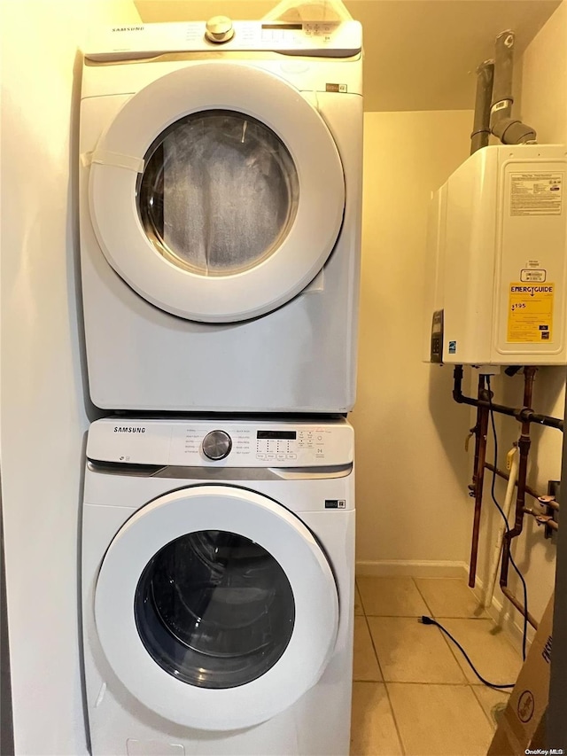 laundry room featuring light tile patterned floors, stacked washer and dryer, and water heater