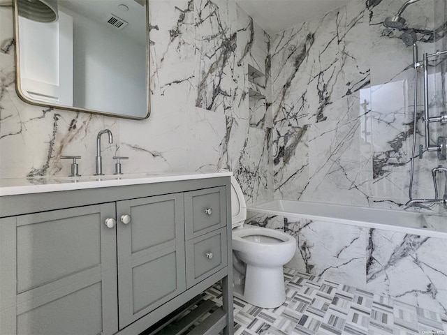 full bathroom featuring tile walls, vanity, tiled shower / bath combo, and toilet