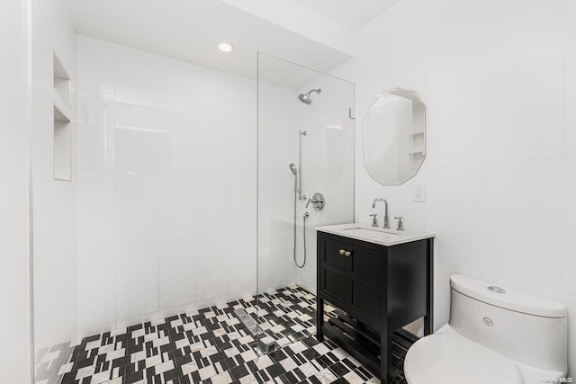 bathroom featuring a tile shower, vanity, toilet, and tile walls