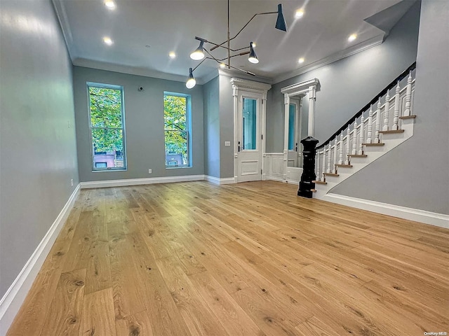 entryway featuring ornamental molding, a notable chandelier, and light wood-type flooring