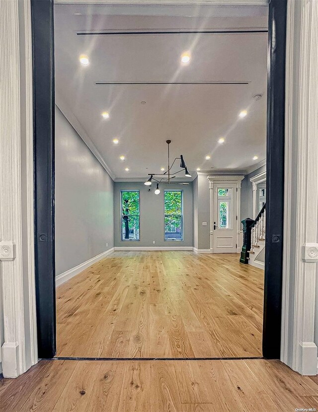 unfurnished living room with crown molding and light hardwood / wood-style flooring