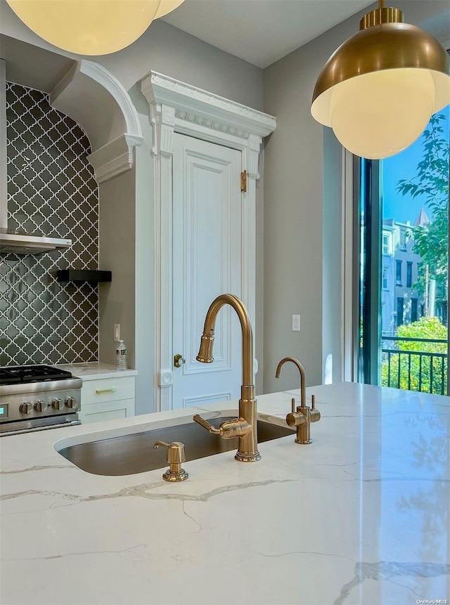 interior space with sink, light stone counters, backsplash, and stainless steel stove