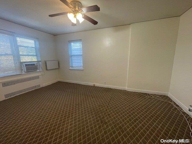 carpeted spare room with ceiling fan, cooling unit, and radiator