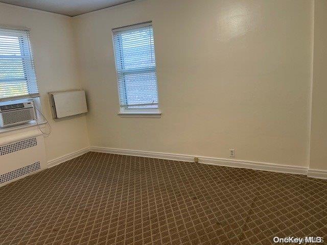 carpeted spare room featuring cooling unit and radiator heating unit