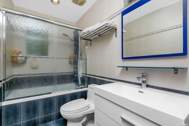 full bathroom featuring vanity, toilet, tile walls, and enclosed tub / shower combo