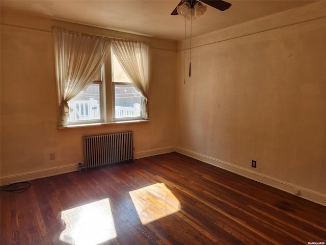 empty room featuring ceiling fan, dark hardwood / wood-style flooring, and radiator