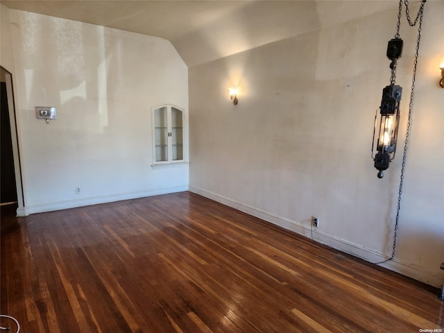 spare room with dark hardwood / wood-style floors and vaulted ceiling