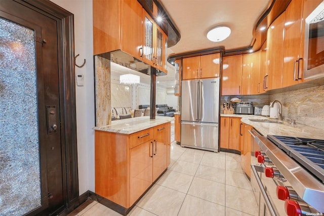 kitchen featuring backsplash, sink, light tile patterned flooring, appliances with stainless steel finishes, and light stone counters