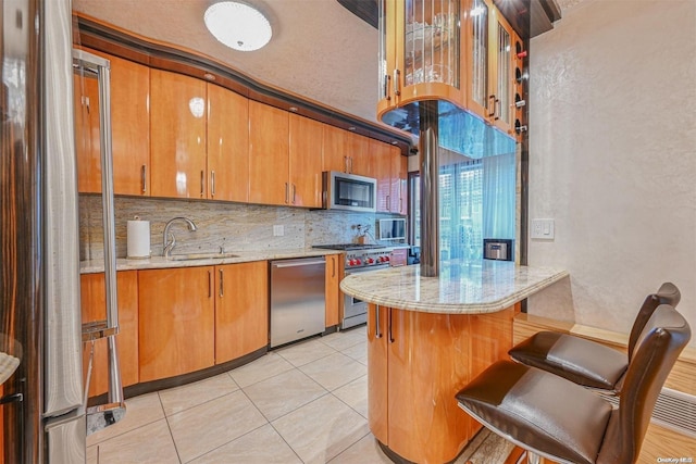 kitchen featuring decorative backsplash, sink, a breakfast bar area, stainless steel appliances, and light tile patterned floors