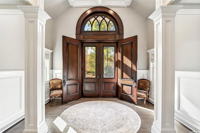 foyer entrance with lofted ceiling, wood-type flooring, ornamental molding, and french doors