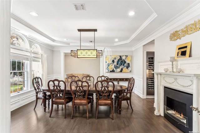 dining space with a raised ceiling, dark hardwood / wood-style flooring, and ornamental molding