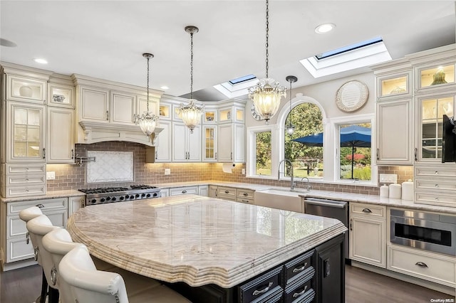 kitchen featuring a skylight, a center island, sink, stainless steel appliances, and decorative backsplash