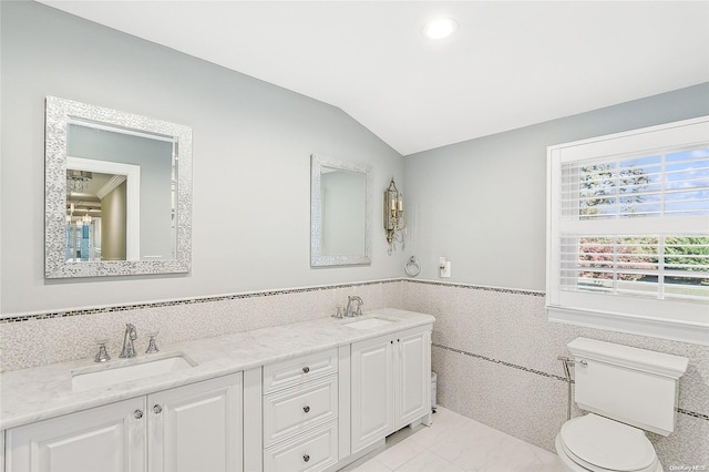 bathroom featuring vanity, toilet, lofted ceiling, and tile walls