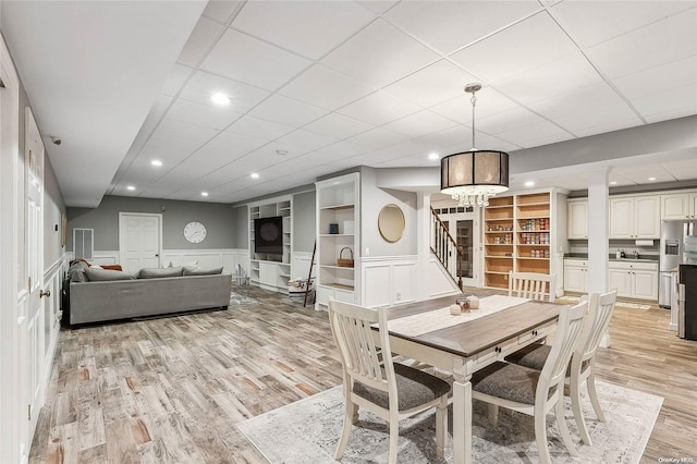 dining area with a paneled ceiling, light hardwood / wood-style flooring, and an inviting chandelier