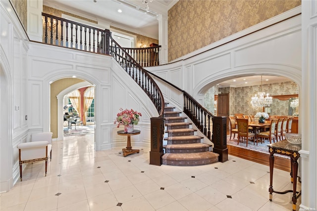 entryway with ornamental molding, a towering ceiling, and a chandelier