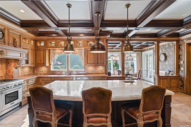 kitchen with decorative backsplash, high end stove, light stone counters, and hanging light fixtures