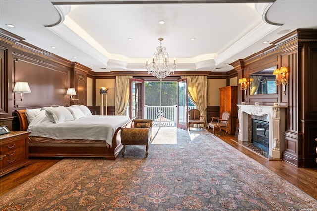 bedroom with dark hardwood / wood-style floors, crown molding, a high end fireplace, and a tray ceiling