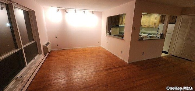 empty room with track lighting and hardwood / wood-style flooring