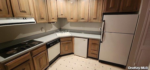 kitchen with white appliances, sink, and range hood