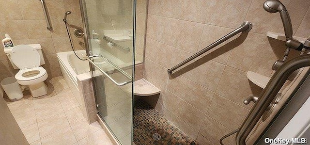 bathroom with tile patterned flooring, separate shower and tub, toilet, and tile walls