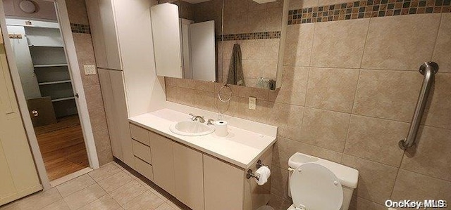 bathroom featuring tile patterned floors, vanity, walk in shower, and tile walls