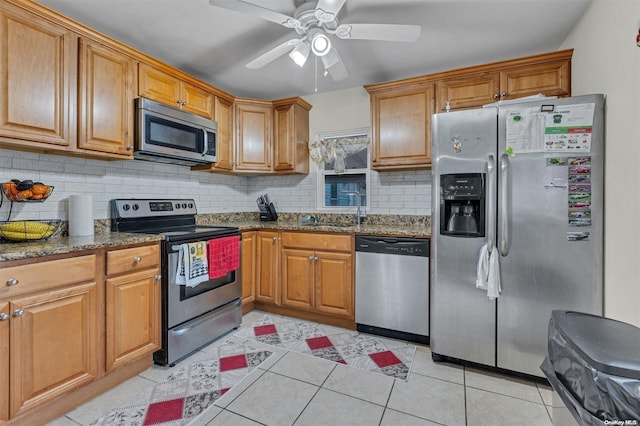 kitchen featuring appliances with stainless steel finishes, light tile patterned floors, ceiling fan, and dark stone counters