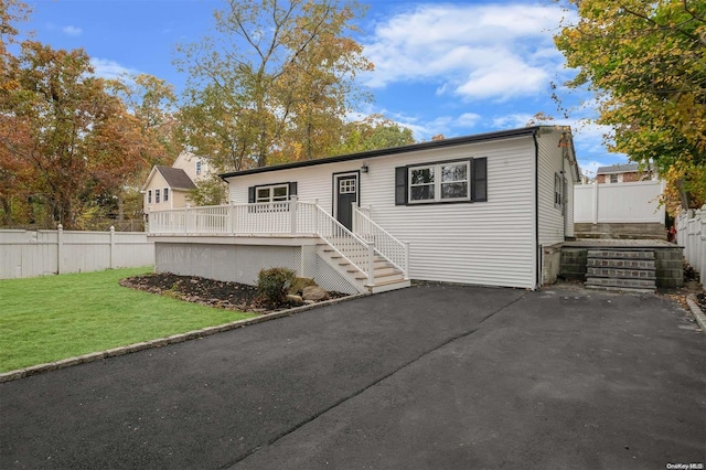 view of front of house with a wooden deck and a front yard