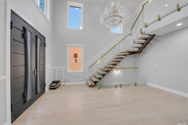 entrance foyer featuring a towering ceiling, a chandelier, and light hardwood / wood-style floors