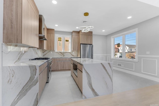 kitchen with pendant lighting, a center island, wall chimney exhaust hood, light stone countertops, and appliances with stainless steel finishes