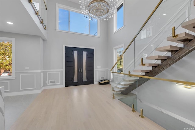 foyer entrance featuring a notable chandelier, a high ceiling, and light hardwood / wood-style flooring