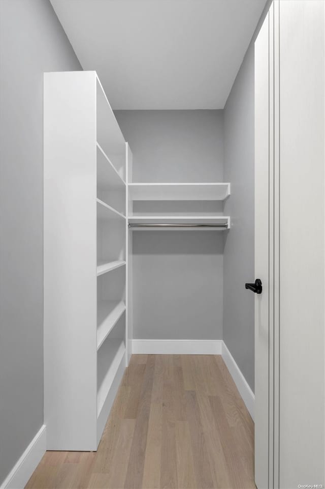 walk in closet with light hardwood / wood-style floors