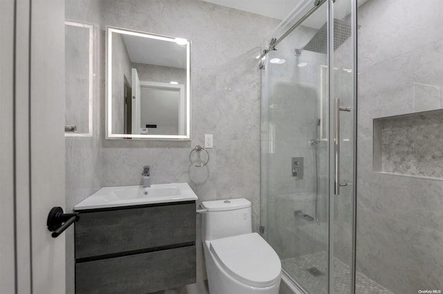 bathroom with a shower with door, vanity, and toilet