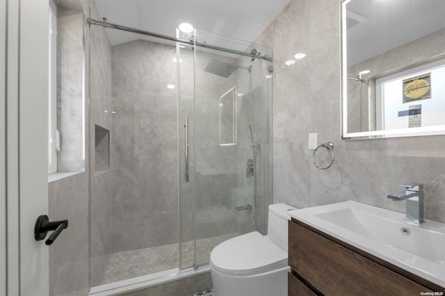 bathroom with vanity, toilet, tile walls, and a shower with shower door