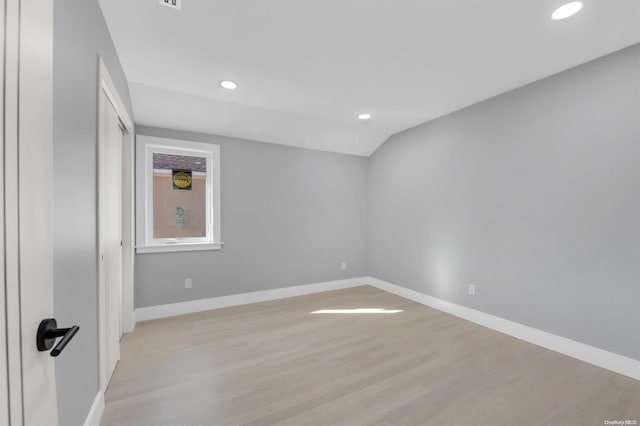 unfurnished room featuring vaulted ceiling and light hardwood / wood-style flooring