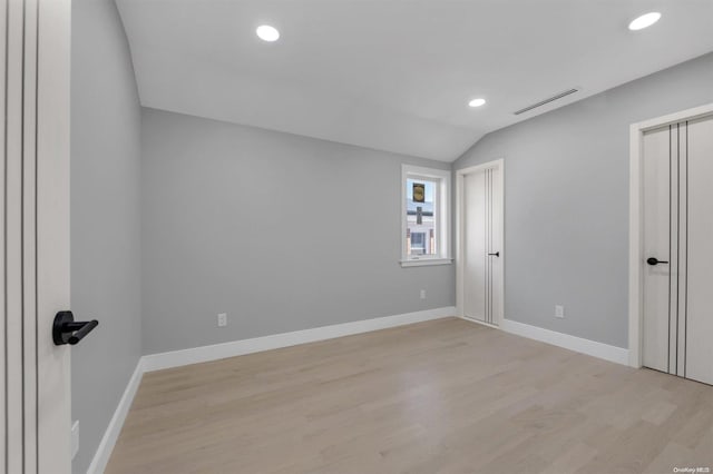 unfurnished room with light wood-type flooring and vaulted ceiling