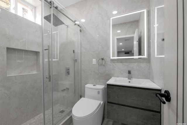 bathroom featuring walk in shower, vanity, toilet, and tile walls