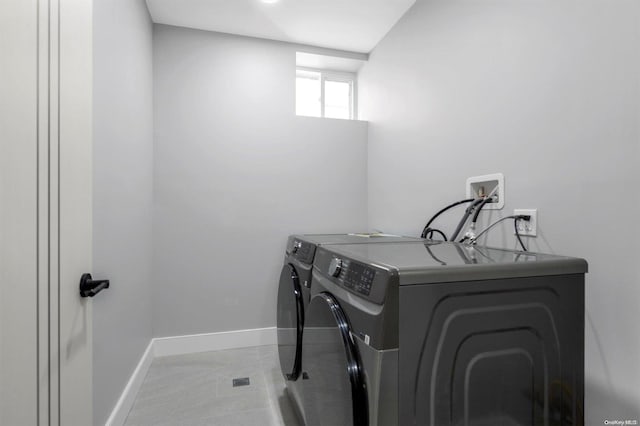 laundry area with washer and clothes dryer and light tile patterned floors