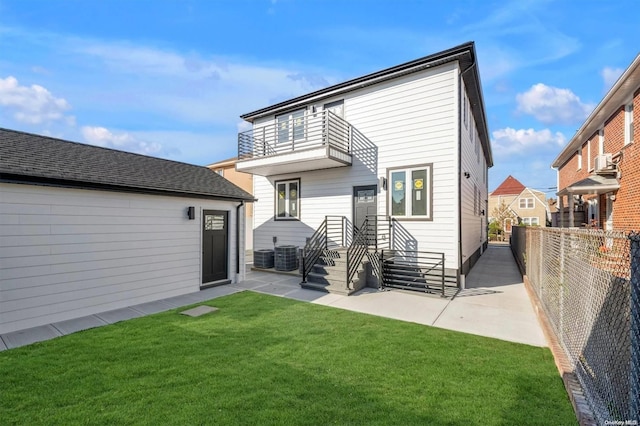 rear view of property with a balcony, a patio area, and a lawn