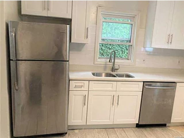 kitchen with white cabinets, sink, tasteful backsplash, light hardwood / wood-style floors, and stainless steel appliances