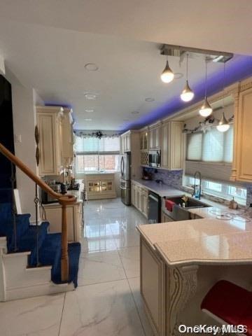 kitchen featuring sink, tasteful backsplash, decorative light fixtures, kitchen peninsula, and stainless steel appliances