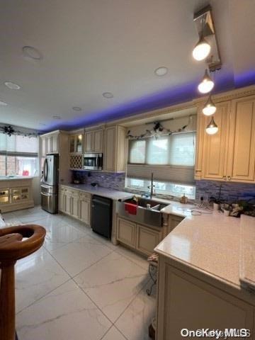 kitchen with light brown cabinets, sink, decorative backsplash, decorative light fixtures, and stainless steel appliances