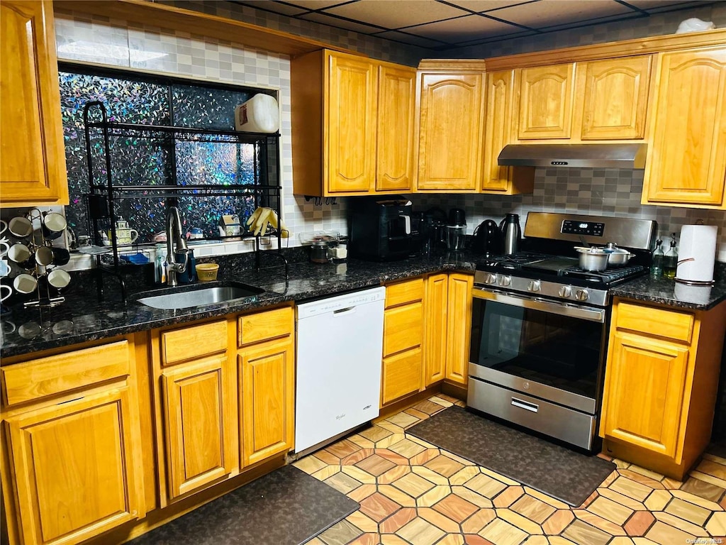 kitchen with decorative backsplash, gas range, white dishwasher, sink, and dark stone countertops