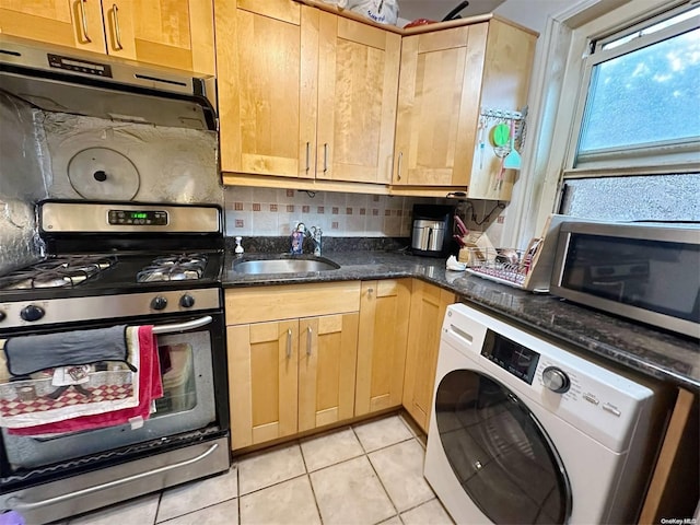 kitchen with sink, stainless steel appliances, washer / dryer, decorative backsplash, and light tile patterned floors