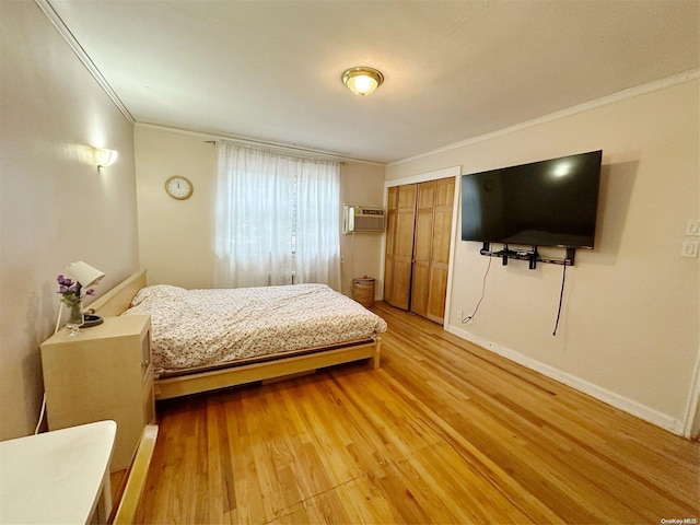 bedroom featuring a closet, light hardwood / wood-style flooring, a wall mounted air conditioner, and ornamental molding