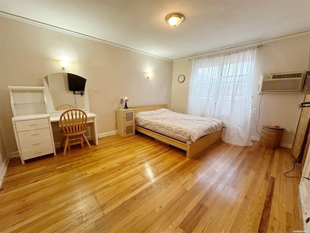 bedroom with a wall mounted AC, light hardwood / wood-style flooring, and ornamental molding