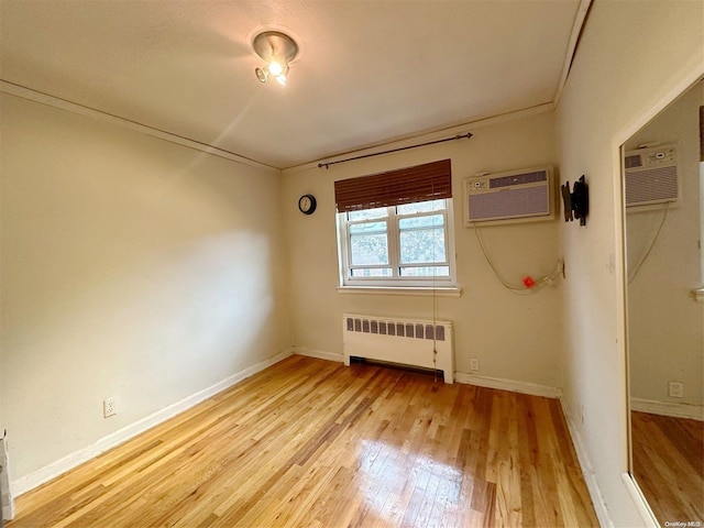 empty room featuring light hardwood / wood-style floors, radiator heating unit, and a wall unit AC