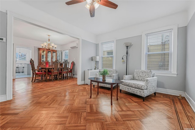 living area with a wall mounted air conditioner, ceiling fan with notable chandelier, a healthy amount of sunlight, and light parquet flooring